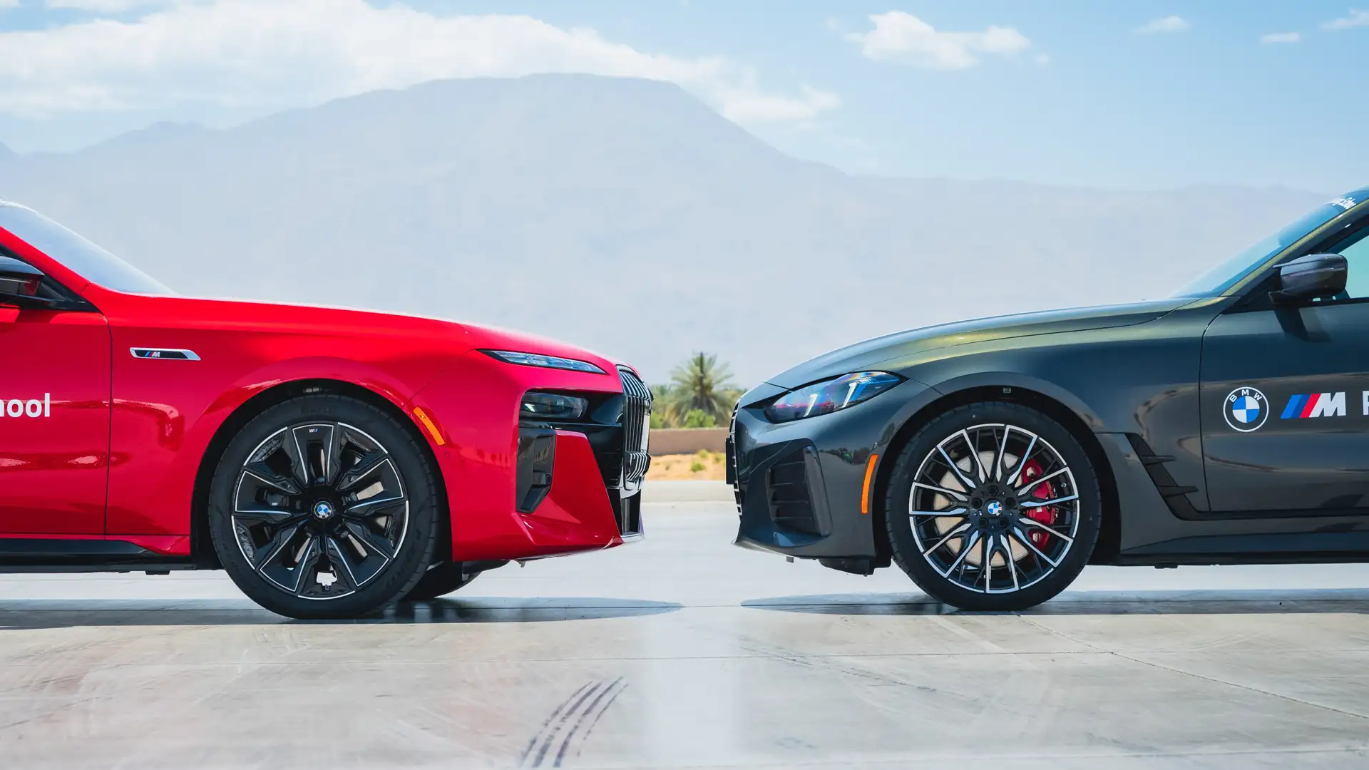 Red and black BMW i4s parked nose to nose against desert mountains