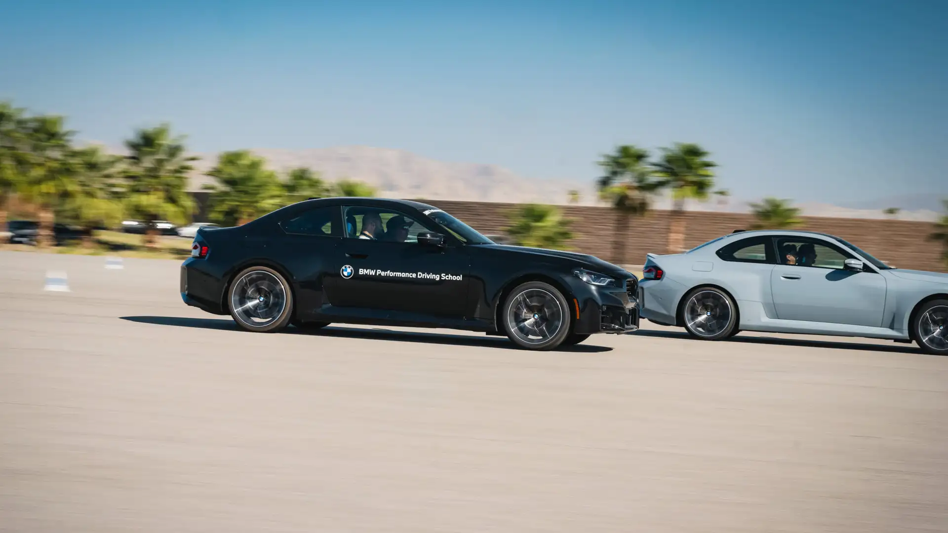 Black and white BMW M2s accelerating side by side