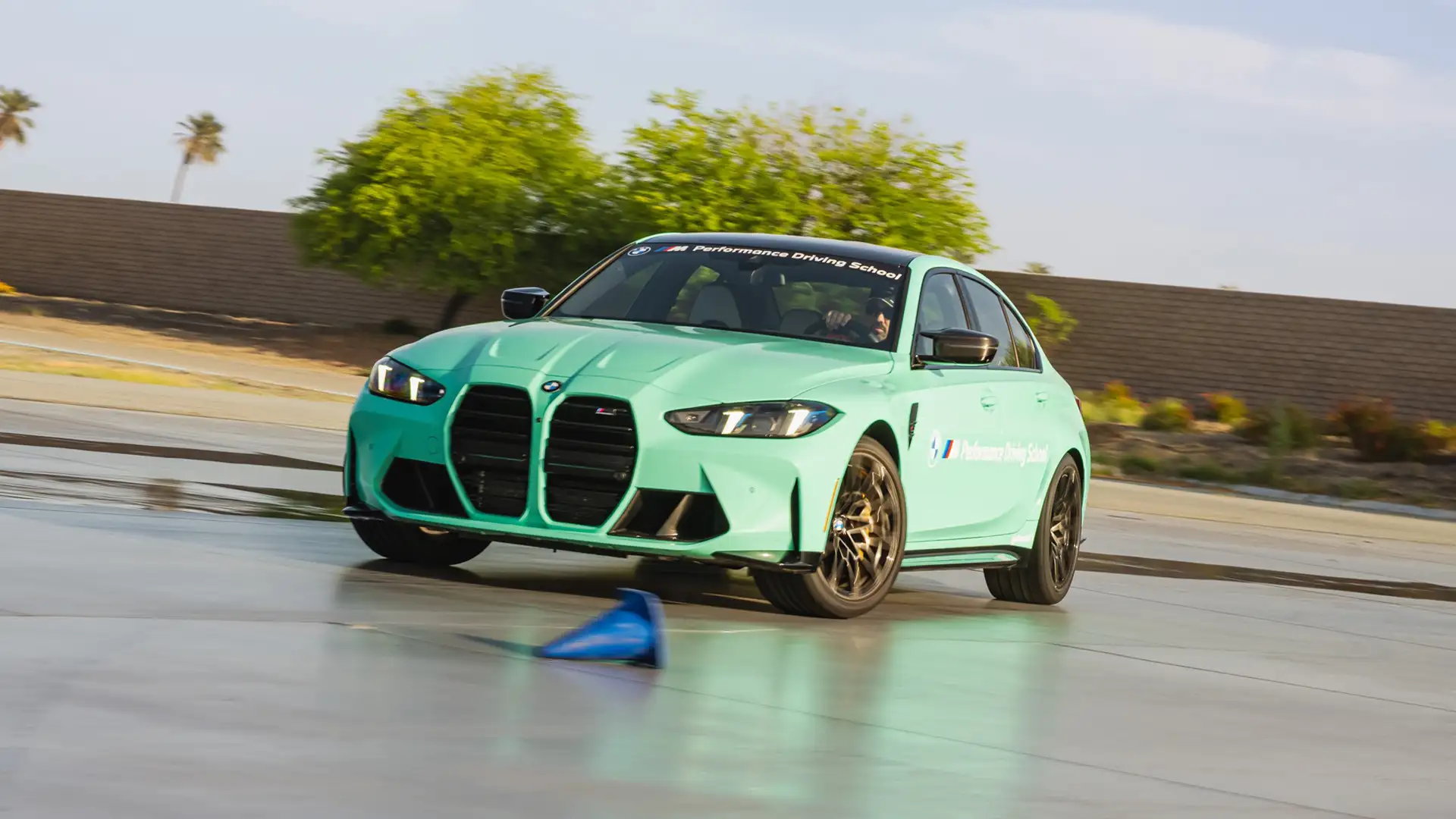 Mint green BMW M3 drifting past a course marker