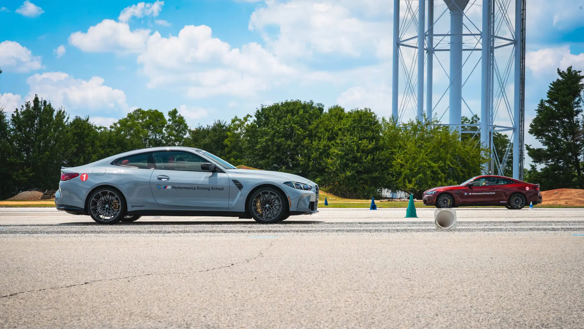 Silver and red BMW M4s lined up for an exercise beside the water tower
