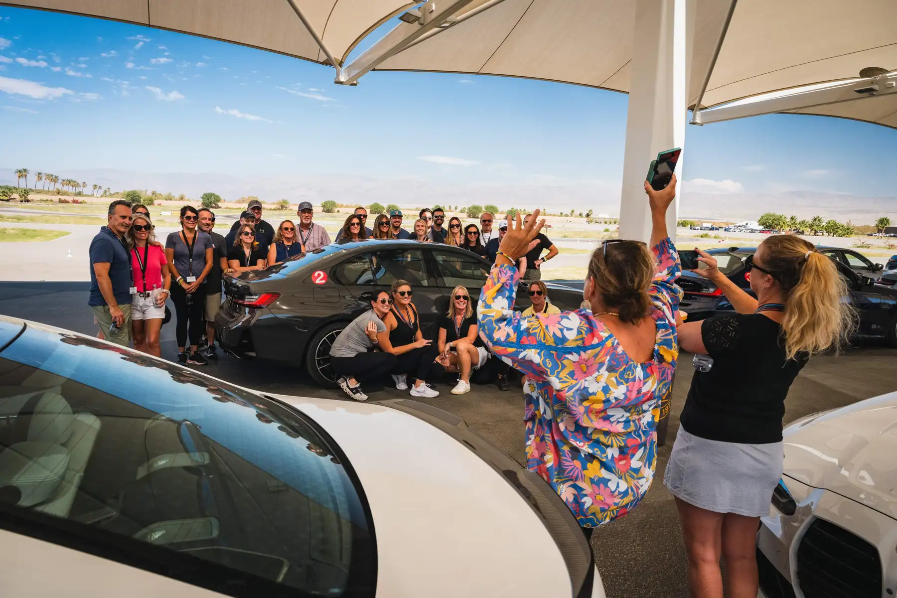 Group posing for a photo beside a BMW in the desert paddock