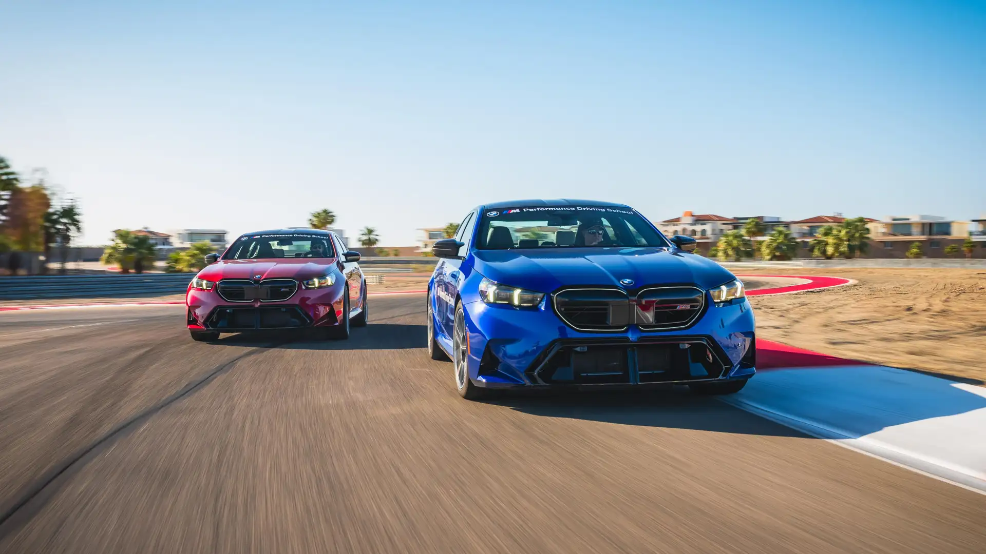 Blue and red BMW M5s running nose to tail on the desert circuit