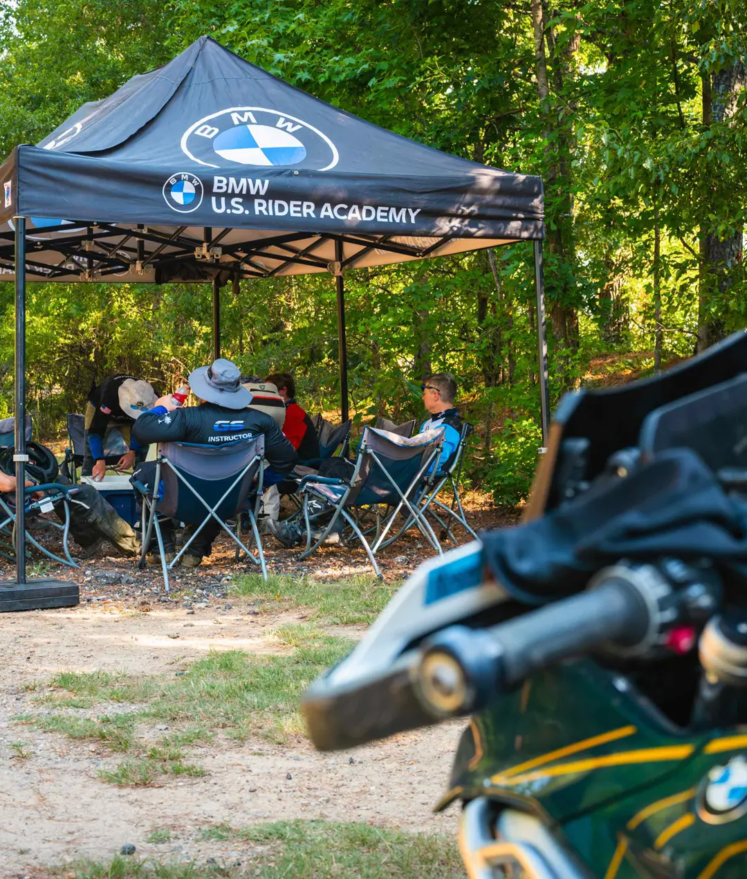 Riders resting under the BMW U.S. Rider Academy canopy between sessions