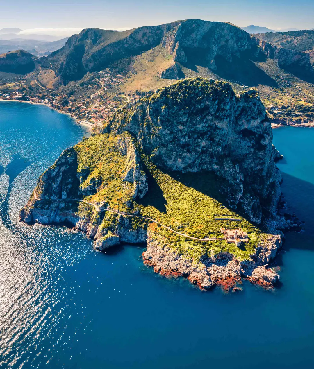 Aerial view of a rocky headland above turquoise sea in Sicily