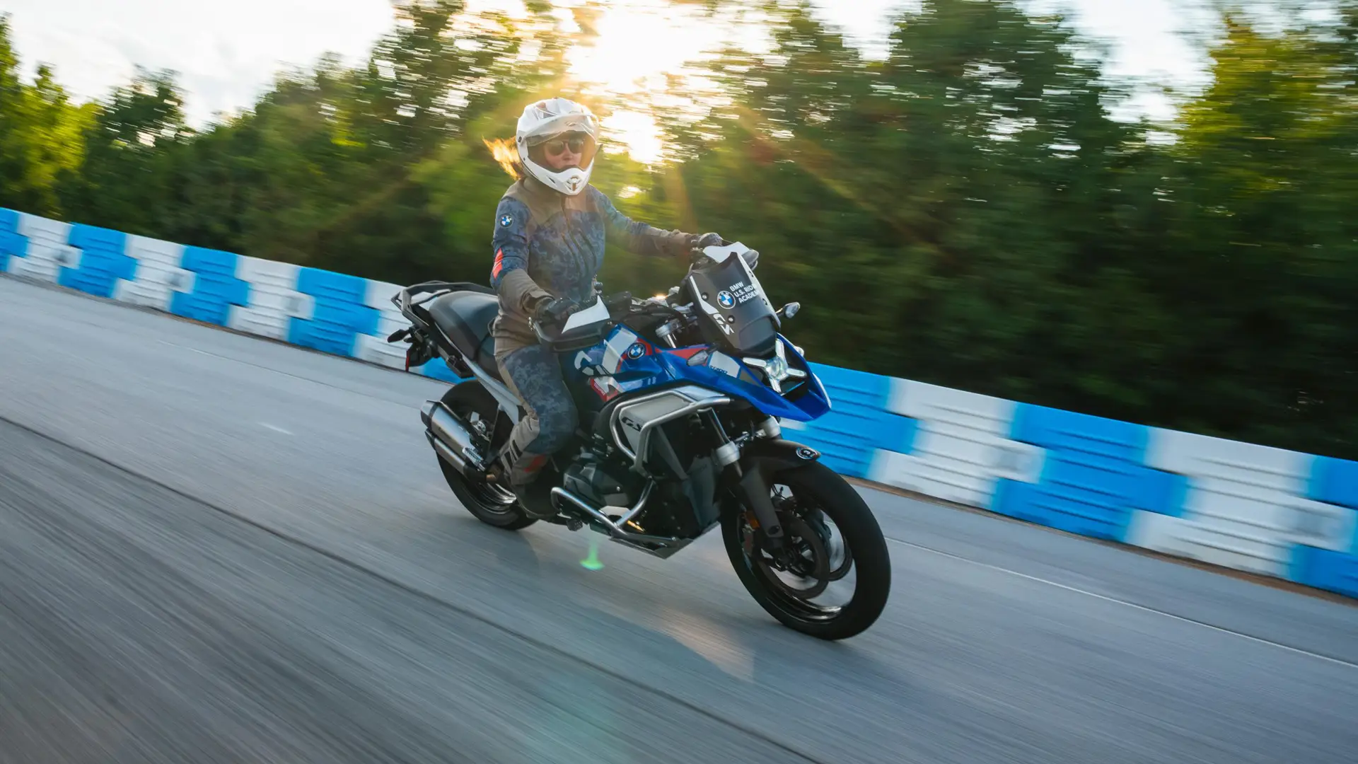 Rider cornering a BMW GS past blue barriers at sunset