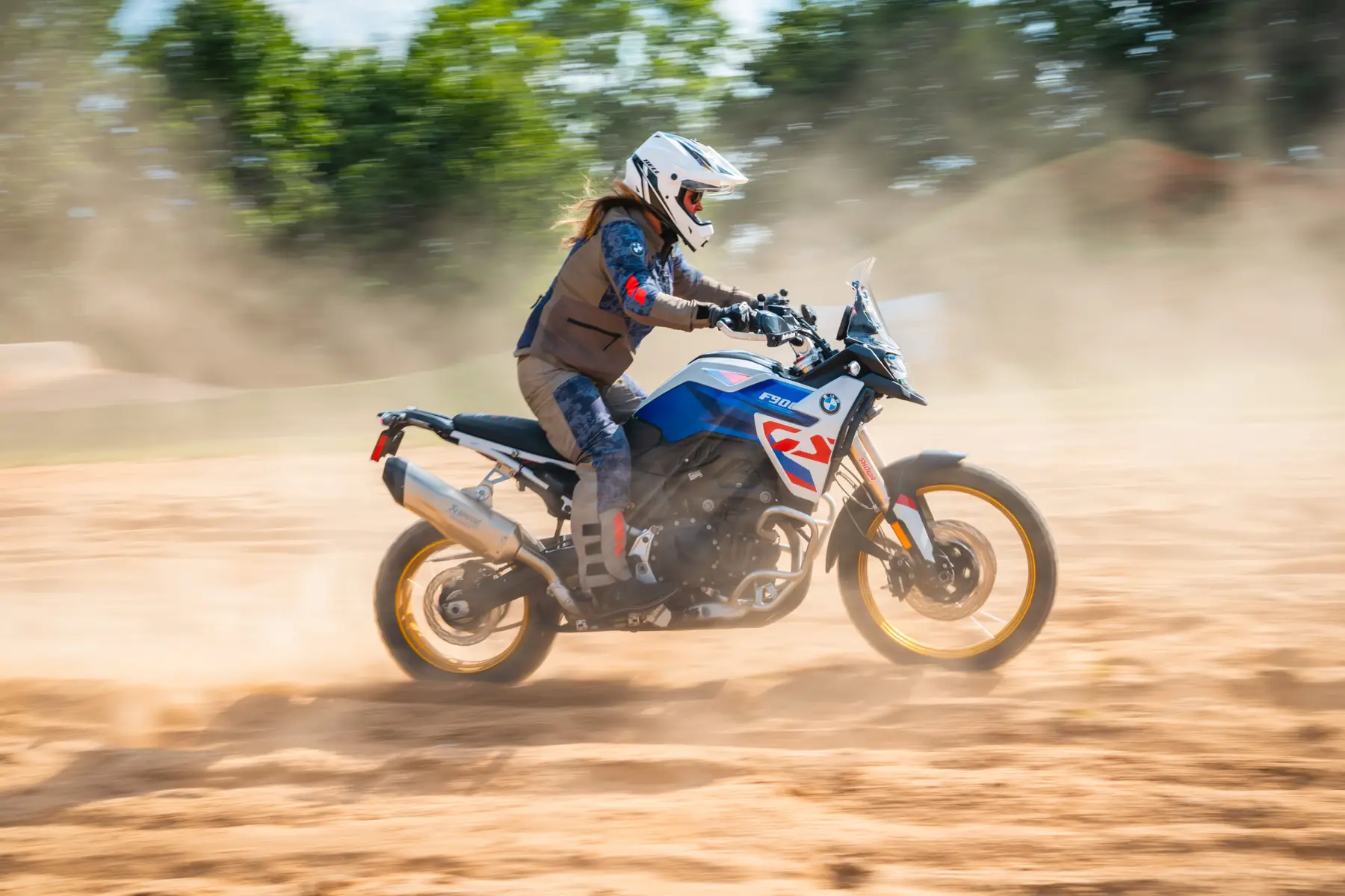 Rider on a BMW F 900 GS at speed across a dusty off-road course