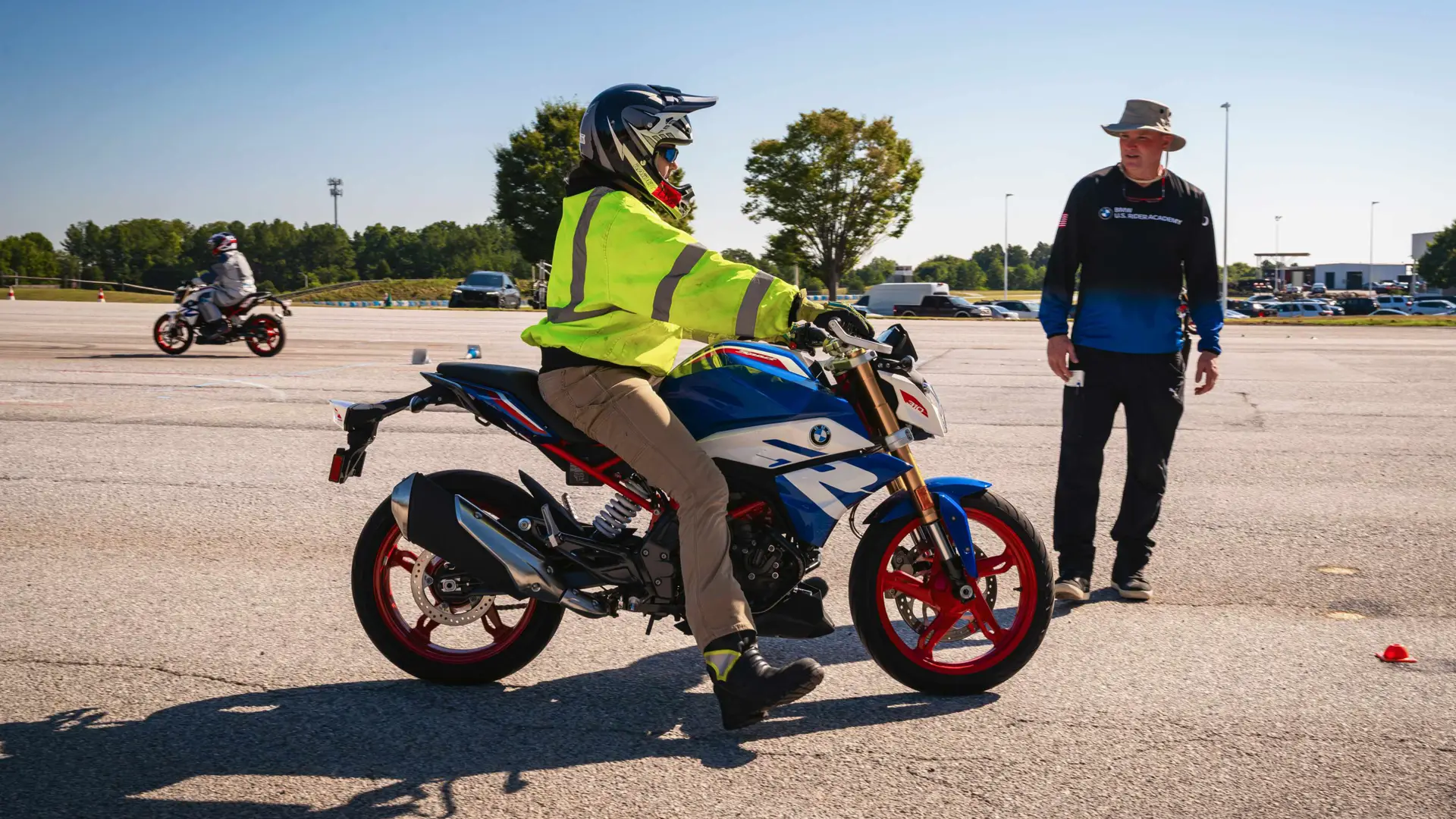 Instructor watching a learner in a high-visibility vest come to a stop