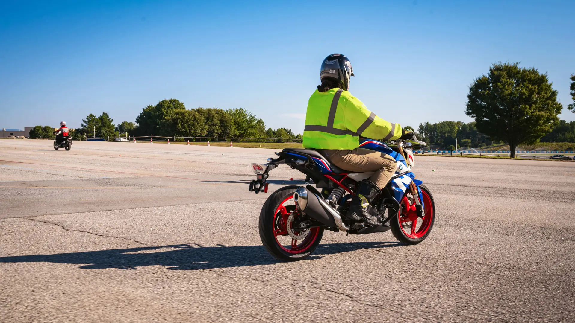 Learner in a high-visibility vest riding away across the training pad