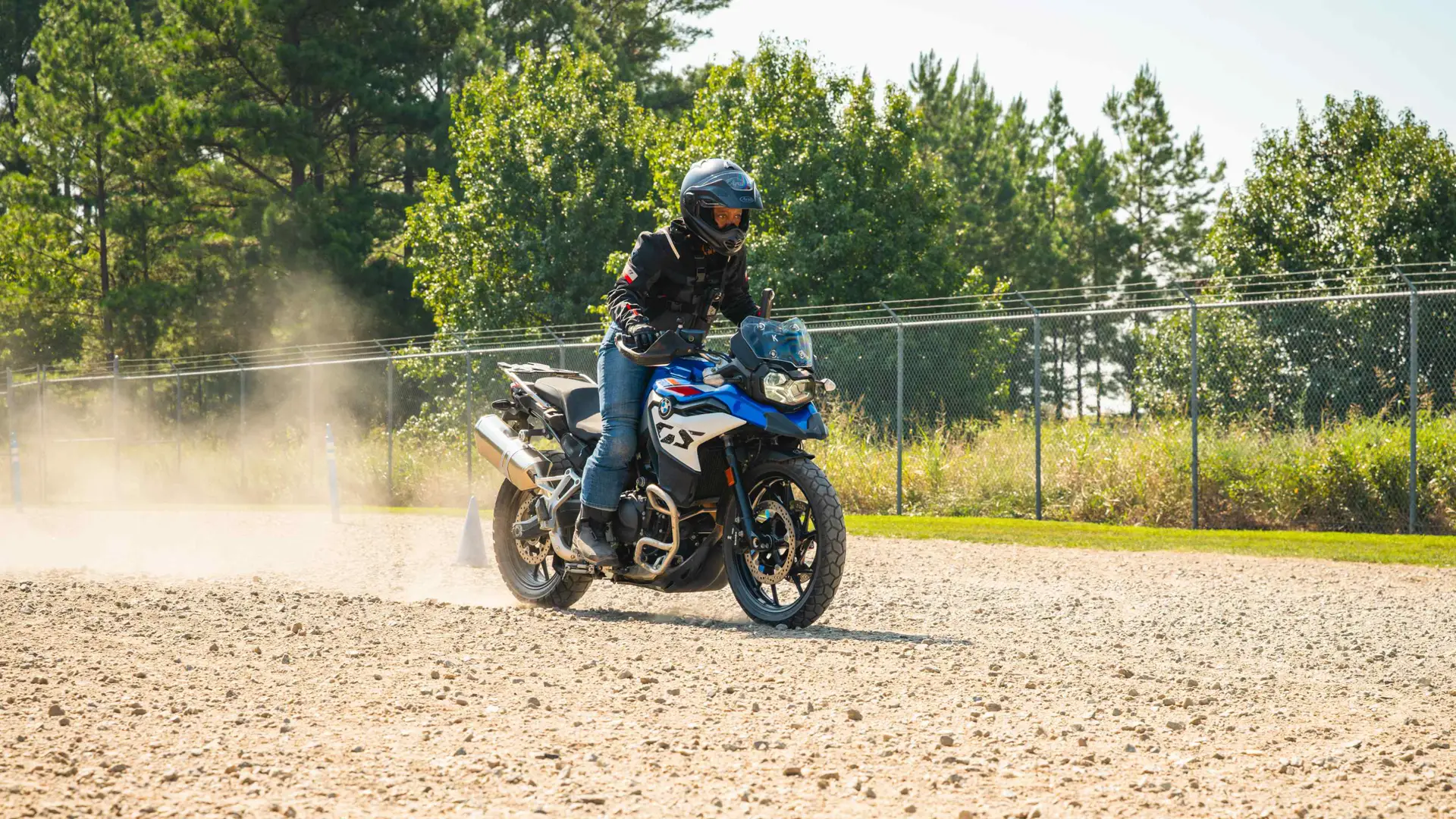 Rider steering a BMW F 900 GS across a loose gravel surface