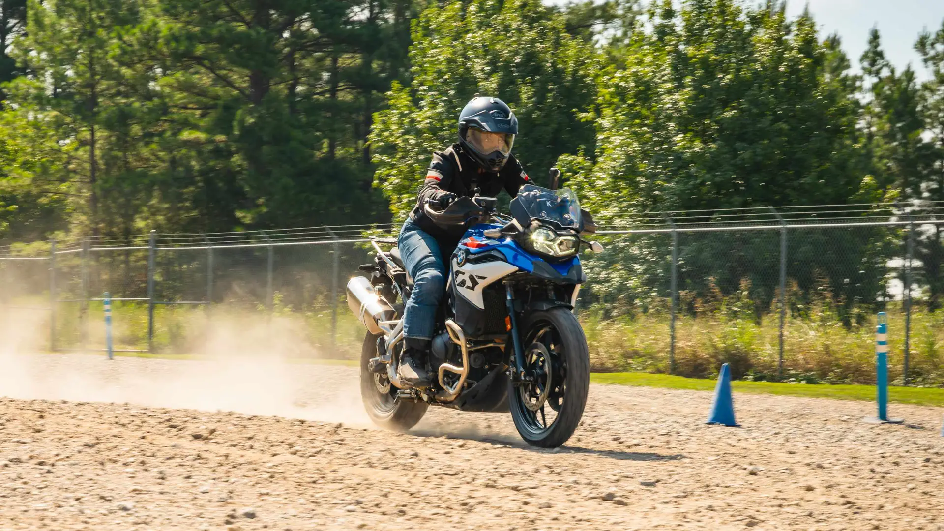 Rider raising dust on a BMW F 900 GS across a sand section