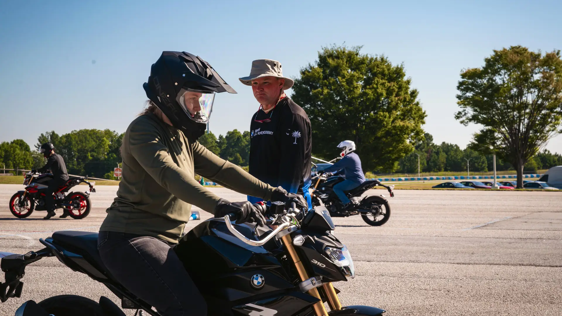 Instructor standing beside a learner seated on a BMW G 310 R