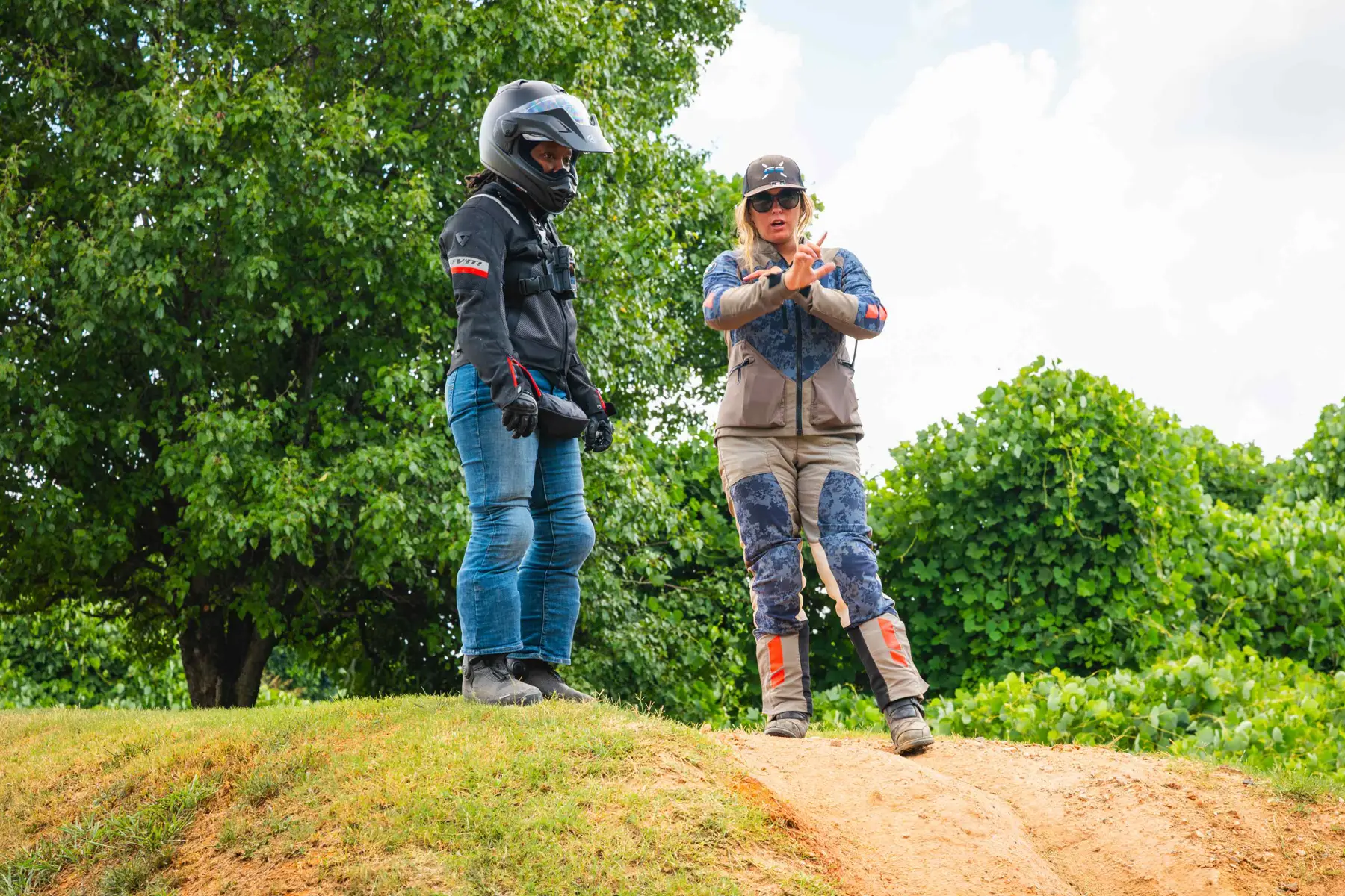 Instructor talking a rider through a technique at the top of a dirt hill