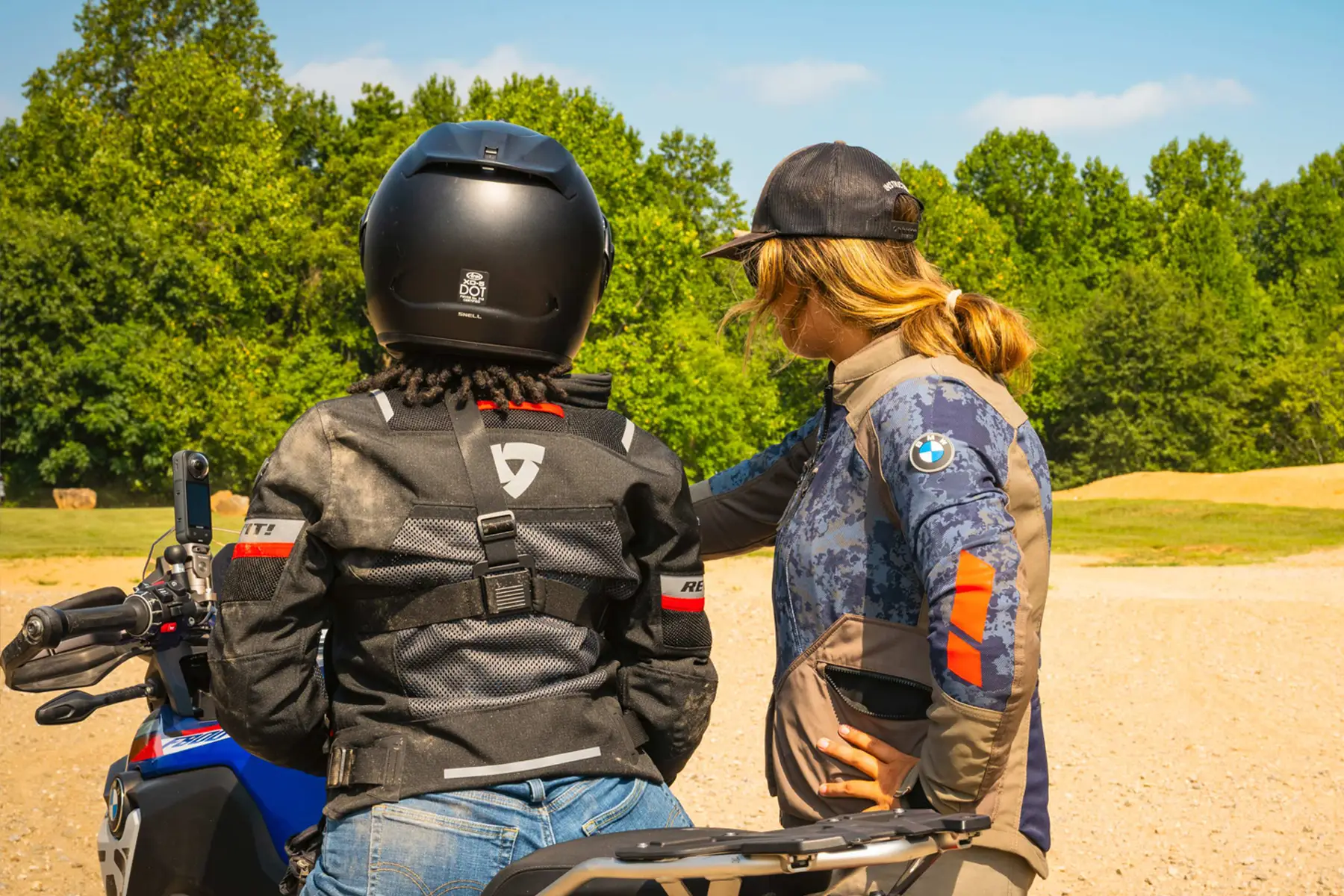 Instructor with a hand on a rider's shoulder beside a BMW GS