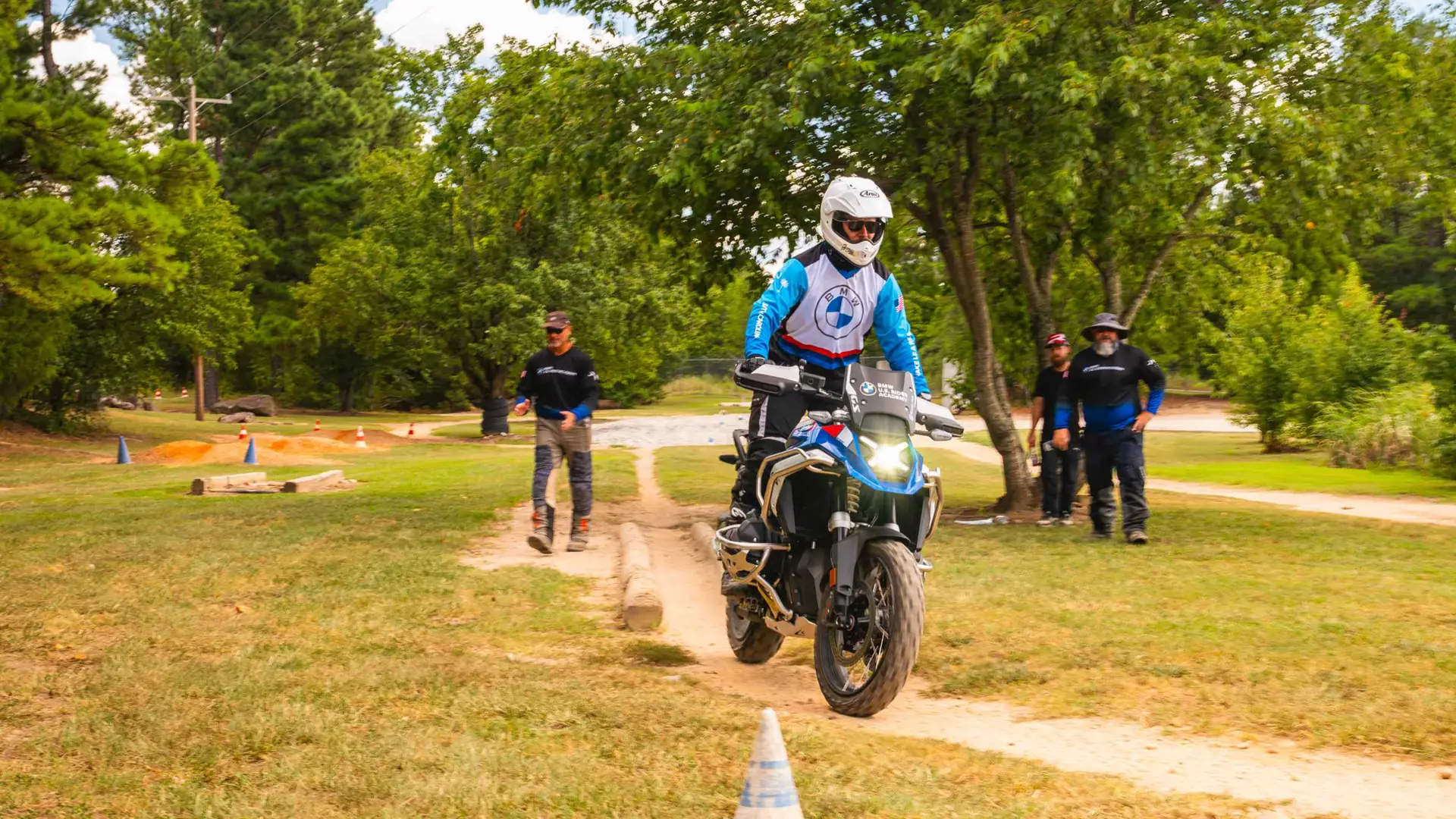 Rider riding a BMW GS along a grass trail as instructors watch