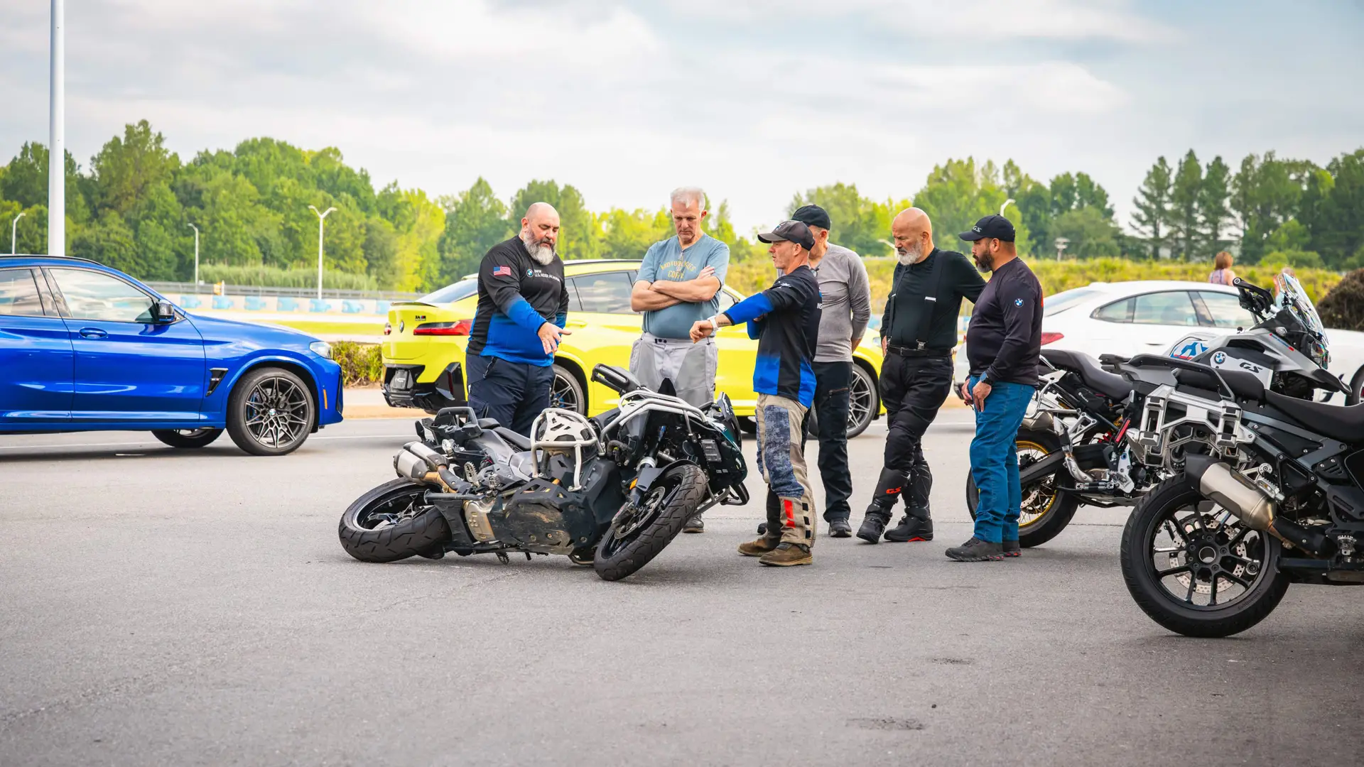 Instructor demonstrating how to lift a fallen motorcycle to a group of riders
