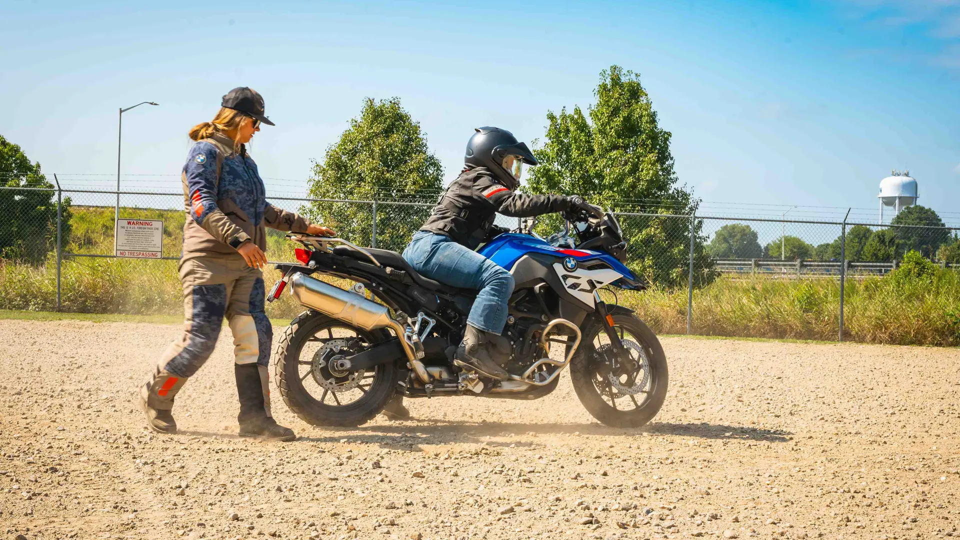 Instructor steadying a BMW GS as a rider sets off on gravel