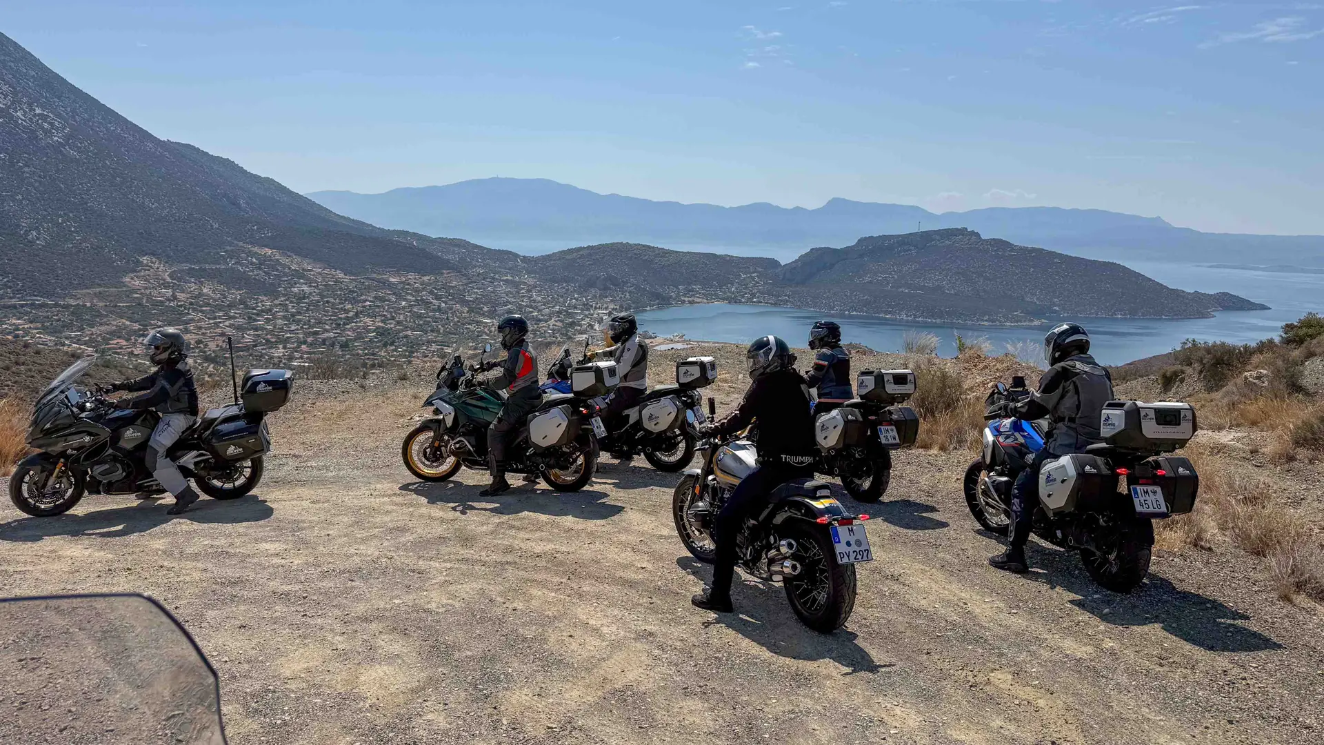Riders parked at a hilltop viewpoint above a coastal town