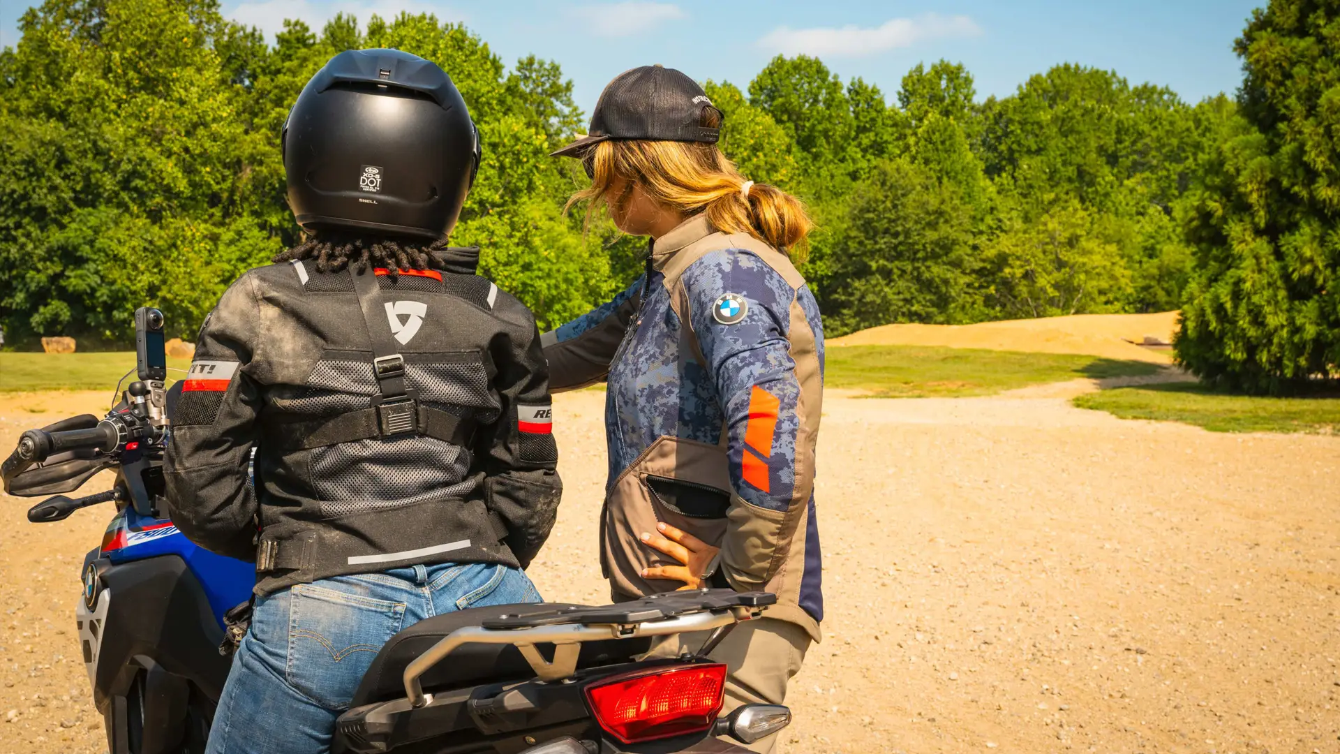 Instructor coaching a rider seated on a BMW GS on a gravel course