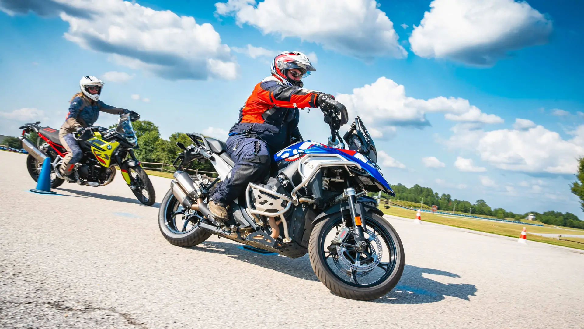 Two riders leaning their motorcycles through a slow-speed turn