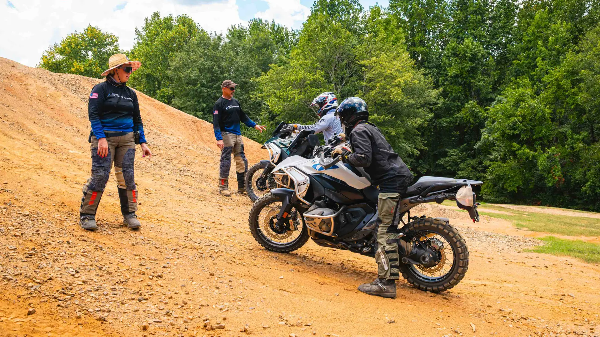 Instructors coaching riders on hill starts and stops on a dirt slope