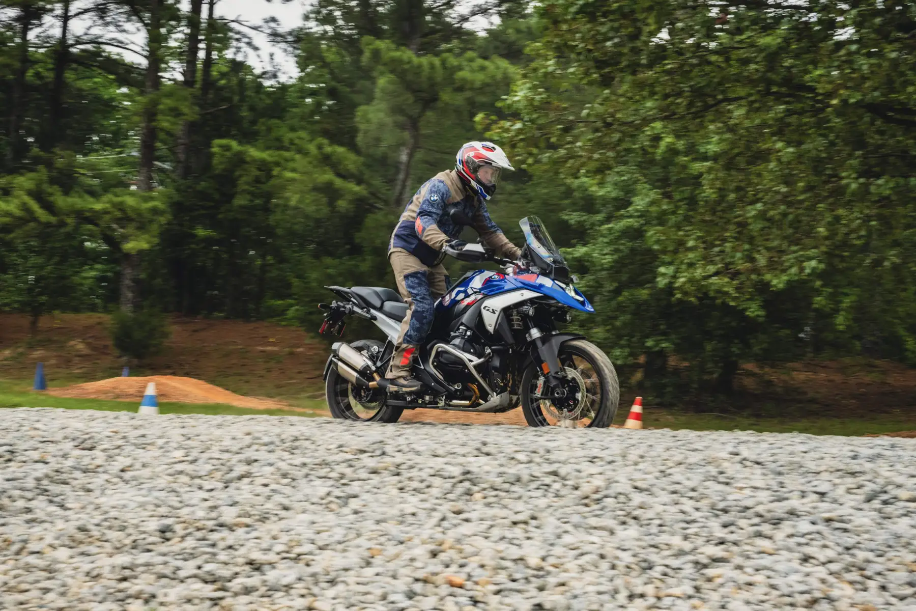 Rider on a BMW GS riding a gravel section beside the pines