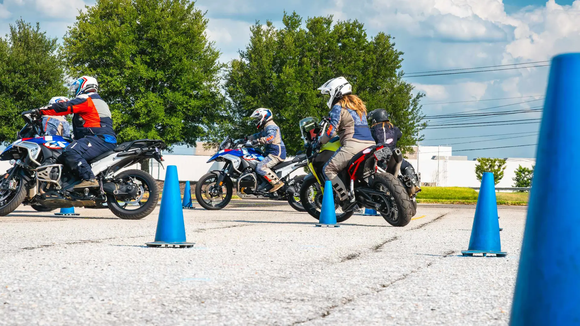 Riders lined up on their motorcycles behind a row of cones