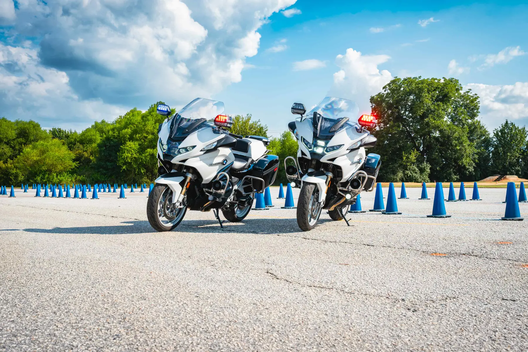 Two white BMW police motorcycles parked before a grid of cones