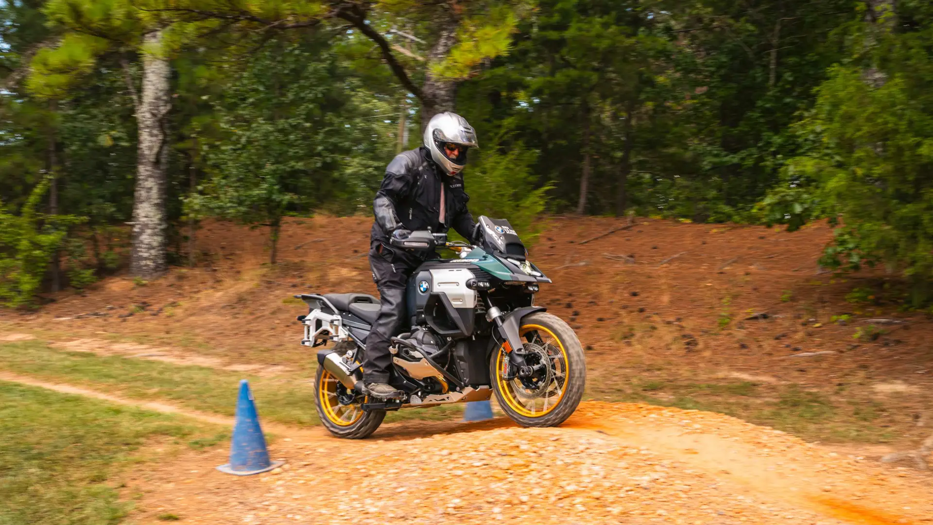 Rider on a BMW GS negotiating a rutted dirt trail marked with cones