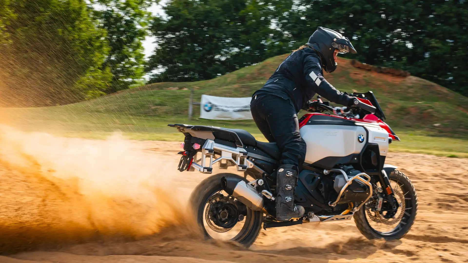 Rider standing on the pegs as a BMW GS throws a rooster tail of sand