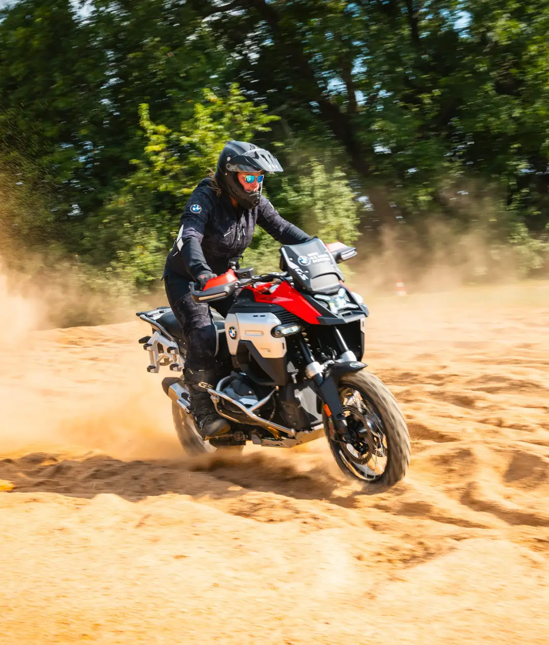 Rider throwing up sand on a red BMW GS in the sand pit